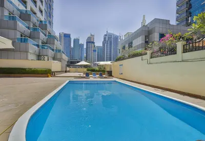 a large blue swimming pool with a city skyline in the background at Near Metro Station - 1BR in Marina Diamond 3, Dubai Marina - Allsopp & Allsopp in Dubai