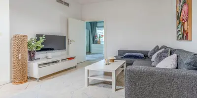 a living room with a couch and a tv at 8min Walk from JBR beach Stylish 1-Bedroom Apartment in Dubai Marina in Dubai