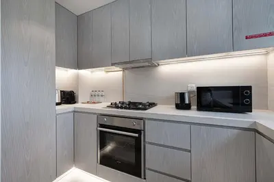 a kitchen with a stove and a microwave at Stylish 1BR with Spacious Terrace Near Circle Mall in Dubai