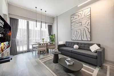 a living room with a couch and a dining room at Stylish 1BR with Spacious Terrace Near Circle Mall in Dubai