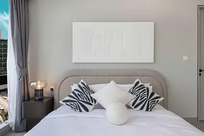 a white bed with black and white pillows at Stylish 1BR with Spacious Terrace Near Circle Mall in Dubai