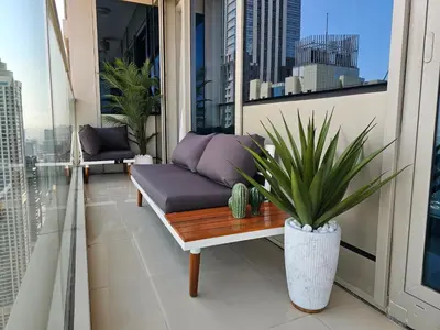 a balcony with a couch and a potted plant at New Renovated Stylish 1 Br Dubai View 73 Floor in Dubai