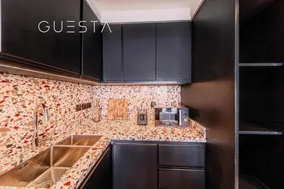a kitchen with black cabinets and a sink at Emaar Beachfront - Sunrise Bay Tower 1, Dubai Marina in Dubai