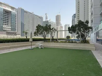 a green lawn in the middle of a city at Luxury2BR Canal View Free parking & water Downtown in Dubai