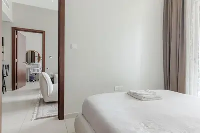 a bedroom with a white bed and a mirror at Luxury2BR Canal View Free parking & water Downtown in Dubai