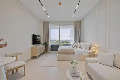 a white bedroom with a bed and a living room at Daniels Studio at Marasi Drive with Canal View in Dubai