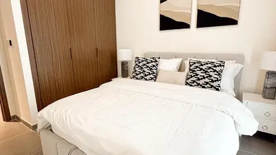 a bedroom with a bed with white sheets and pillows at Luxury 2BHK & Lagoon view in Dubai