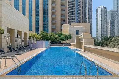 a swimming pool in a hotel with chairs and buildings at Downtown Luxury Large Studio Near Burj Khalifa with City Views, - Claren Tower 1, Downtown Dubai by Deluxe Holiday Homes in Dubai