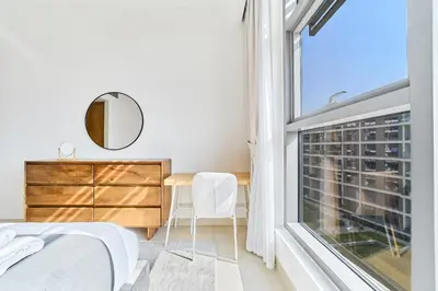 a bedroom with a large window and a table and chair at Chic 2BR in Mulberry with Dubai Hills Park Views in Dubai