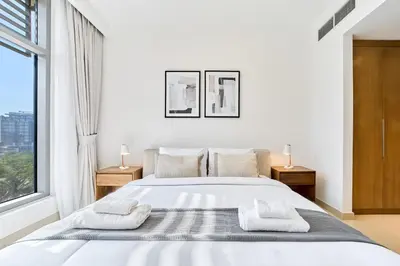 a white bedroom with a large bed and a window at Chic 2BR in Mulberry with Dubai Hills Park Views in Dubai