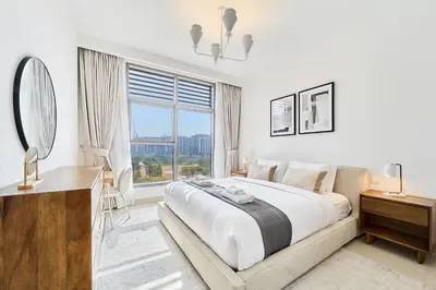 a white bedroom with a large bed and a window at Chic 2BR in Mulberry with Dubai Hills Park Views in Dubai