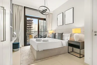 a white bedroom with a large bed and a window at Luxury 3BR Downtown Apt with Burj Khalifa, Dubai Mall & Opera House Views in Dubai