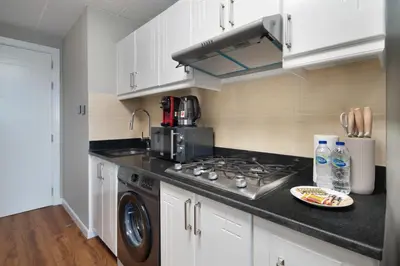 a kitchen with white cabinets and a stove top oven at Studio Aura at Dubai Sports City in Dubai