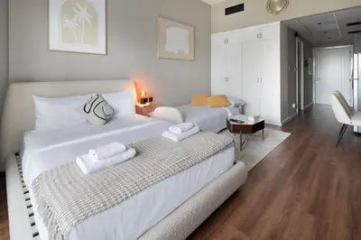 a bedroom with two beds and a living room at Studio Aura at Dubai Sports City in Dubai