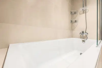 a white bath tub with a shower in a bathroom at FIRST CLASS 2BR Design Meets Comfort in Dubai