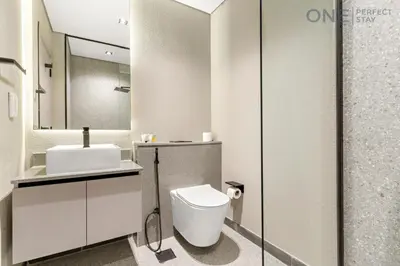 a white bathroom with a toilet and a sink at Modern Cozy Studio in Dubai