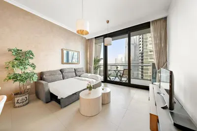 a living room with a couch and a tv at FIRST CLASS 1BR Majestic Burj Khalifa View in Dubai