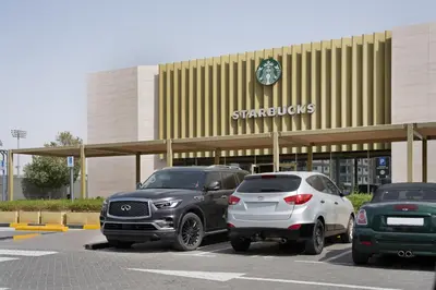 two cars parked in a parking lot in front of a store at Studio Nova at Dubai Sports City in Dubai