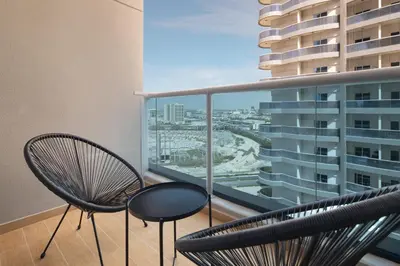 a balcony with two chairs and a view of a city at Studio Nova at Dubai Sports City in Dubai