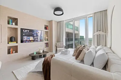 a living room with a white couch and a tv at 41st-Floor 2BR with World's Highest Running Track in Dubai