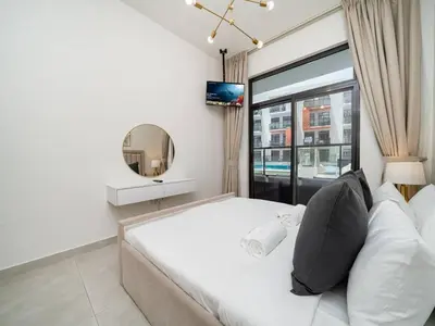 a bedroom with a large white bed and a mirror at Bright and Spacious 1 Bed Prime JVC Location in Dubai