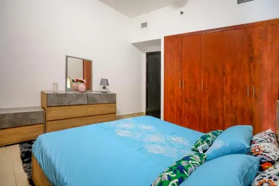 a bedroom with a blue bed and a wooden cabinet at IDLE 1Bed Marina POOL &JBR BEACH in Dubai