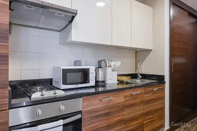 a kitchen with a stove top oven next to a microwave at Charming Studio Retreat -Few steps away from Ocean in Dubai