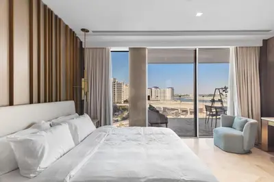 a bedroom with a large white bed and a chair at Sea View 2BDR Apartment, Pool and Beach Access in Dubai