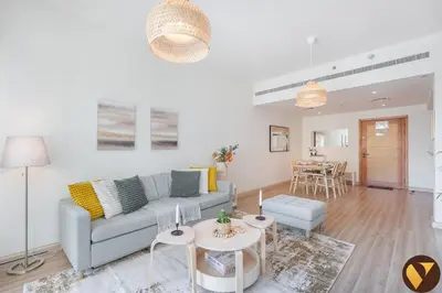 a living room with a couch and a table at Vogue The Greens Al Alka near Mall of the Emirates, One Bedroom Apartment with Balcony and Vibrant community View, Access to all Amenities in Dubai