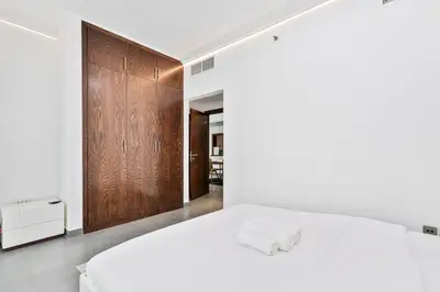 a bedroom with a white bed and a wooden wall at Stylish 2BR with Pool, Gym, Sauna & Kid's Playground in Dubai