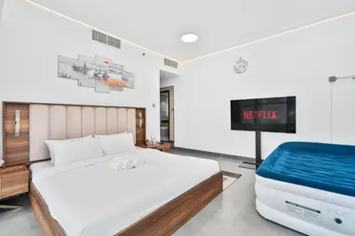 a bedroom with a bed and a flatscreen tv at Stylish 2BR with Pool, Gym, Sauna & Kid's Playground in Dubai