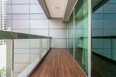 a corridor of a building with glass walls and a wooden floor at Stylish 2BR with Pool, Gym, Sauna & Kid's Playground in Dubai