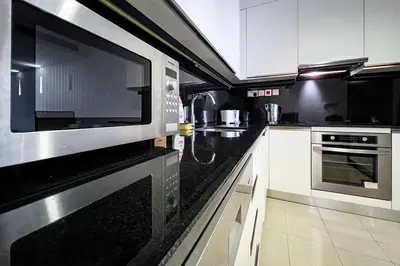 a kitchen with white cabinets and a microwave at Modern 1-Bedroom in Address Marina, City View - 20AB01 in Dubai