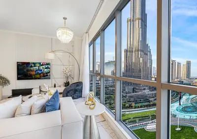 a living room with a white couch and a large window at Livin' Holidays - 2 BR - Burj Khalifa & Fountain in Dubai