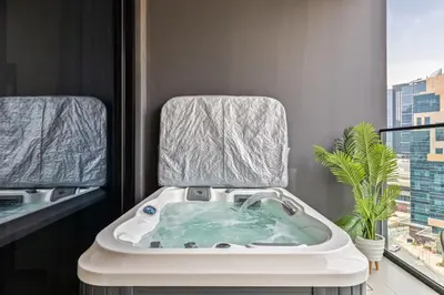 a bathroom with a bath tub with a mirror at Waves - Luxe Studio with Jacuzzi & City Views in Dubai