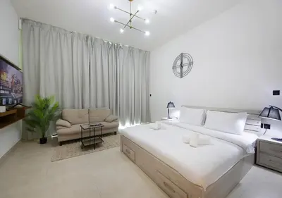 a white bedroom with a large bed and a chair at Elegant Studio in Binghatti Canal, Downtown Access in Dubai