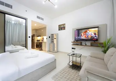 a white bedroom with a large bed and a flat screen tv at Elegant Studio in Binghatti Canal, Downtown Access in Dubai