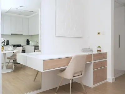 a white kitchen with a desk and chairs at Luxury Furnished, Brand New in Dubai