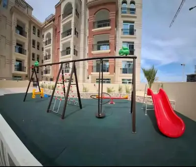 an empty playground with swings and slides in front of a building at Ayla Residence 1 in Dubai