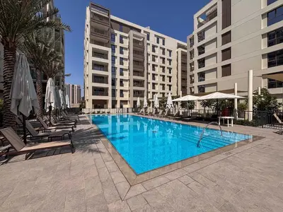a swimming pool with chairs and umbrellas next to a building at Frank Porter - Groove 1 at Creek Beach in Dubai