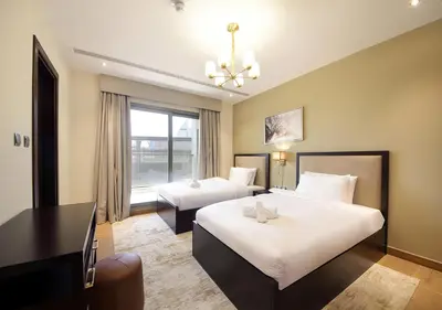 a hotel room with two beds and a desk at 2BR Stylish Elite Apartment Near Burj Khalifa in Dubai