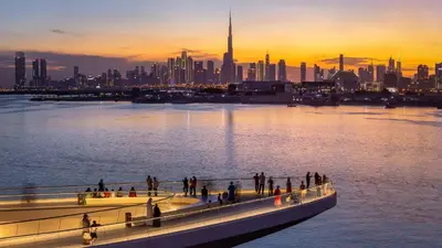 a group of people walking on a bridge over the water at Luxury Apt and Private Beach with cooled sand in Dubai