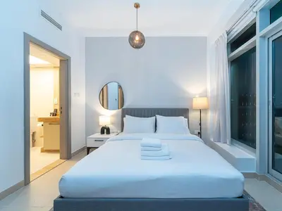 a bedroom with a large white bed and a mirror at Burj Views 3 min from Dubai Mall Luxury DownTown Residence in Dubai