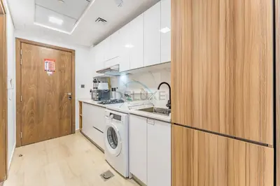 a kitchen with a washing machine and a washer at Pool and Community View Studio with Balcony Near Park, Pantheon Elysee III, Jumeirah Village Circle by Deluxe Holiday Homes in Dubai