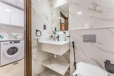 a bathroom with a sink and a washing machine at Pool and Community View Studio with Balcony Near Park, Pantheon Elysee III, Jumeirah Village Circle by Deluxe Holiday Homes in Dubai
