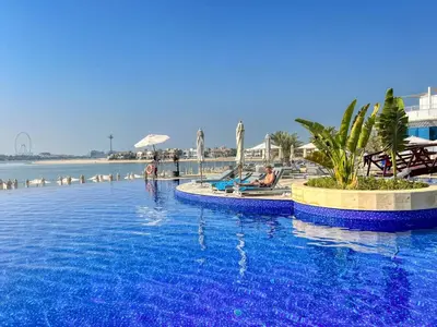 a resort swimming pool with people sitting in the water at Family Beach Home 3BR on Palm Jumeirah with Pool in Dubai