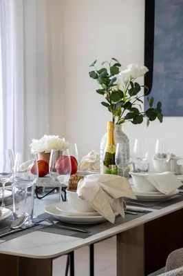 a table with plates and glasses and a vase with flowers at Frank Porter - Murooj Al Furjan West in Dubai