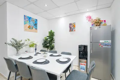 a dining room with a white table and a refrigerator at Berloga Holiday Homes JBR in Dubai