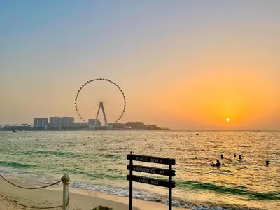 a bench on the beach with the ferris wheel in the background at Berloga Holiday Homes JBR in Dubai