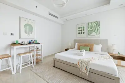 a white bedroom with a bed and a desk at Cozy Studio 7 Minutes From Dubai Mail in Dubai